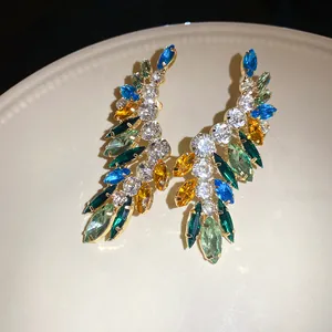 Close-up of elegant wing-shaped earrings with vibrant colorful marquise rhinestones on plate