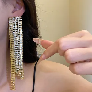 Close-up of elegant gold asymmetric mesh tassel earrings worn by a model