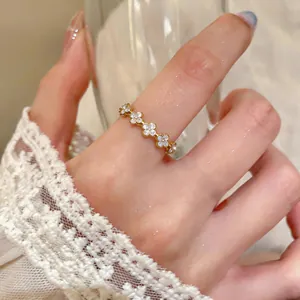 Dettaglio di un delicato anello d'oro con motivi floreali incastonati di zirconi.
