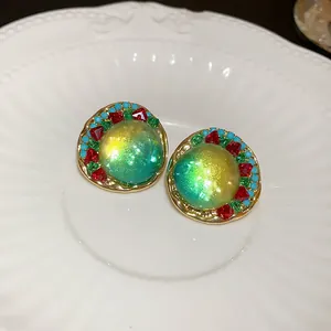Elegant vintage iridescent green stud earrings with colorful stone accents on a white plate