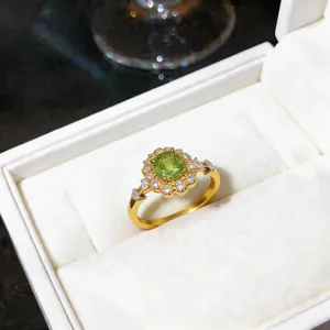 Dettaglio che mostra il design del fiore in zircone verde su un elegante anello d'oro