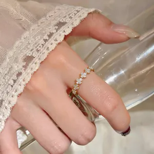 Primo piano dettagliato di un elegante anello a fiore in oro con zirconi sul dito