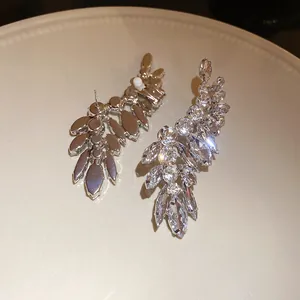 Detail view of sparkling marquise crystal climber earrings on a cream ceramic plate.