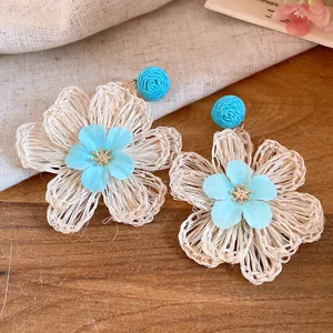 Detailed macro view of handmade beige raffia flower earrings with light blue fabric centers