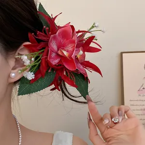 Detailed view of a large red fabric orchid flower hair clip worn by a model.