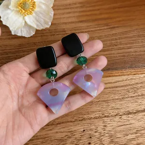 Nahaufnahme eleganter fächerförmiger Harzohrringe mit schwarzem Stecker und grüner Perle
