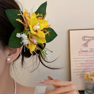 Detailed view of sweet yellow fabric orchid flower hair clip worn on brunette hair.