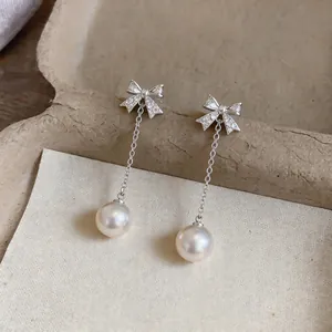 Detail shot of bowknot zircon stud earrings with elegant pearl tassel drops.