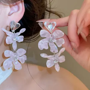Close-up of pink acetic acid flower drop earrings with clear heart studs and rhinestones