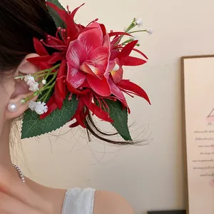 Detailed view of a large red fabric orchid hair clip with green leaves worn on hair