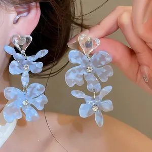 Close-up of blue acetate flower earrings with shimmering crystal center detail