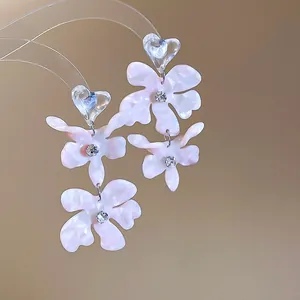 Close-up of pink acetate flower drop earrings with sparkling rhinestone centers.
