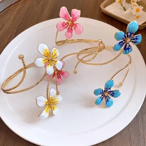 Elegant vintage gold metal arm cuff bracelets featuring colorful enamel flower designs