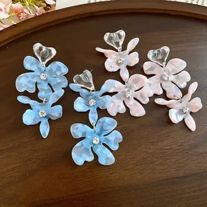 Exquisite close-up of acetate flower drop earrings with sparkling rhinestones and marble texture