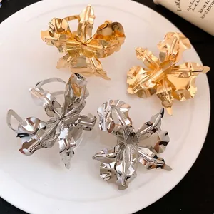 Four metallic floral open rings in gold and silver on a white plate