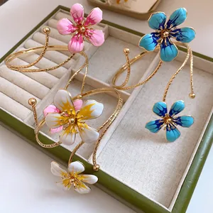 Close-up detail of elegant gold-toned enamel flower arm cuffs in a jewelry display box