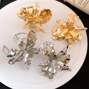 Detailed view of metallic flower rings with textured petals in gold and silver finish.