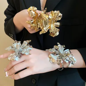Detailed view of large metallic flower rings and bracelets in gold and silver