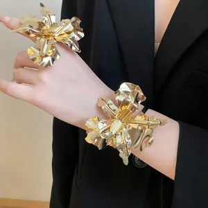 Model wearing a chunky gold metal flower statement ring and matching bracelet set.