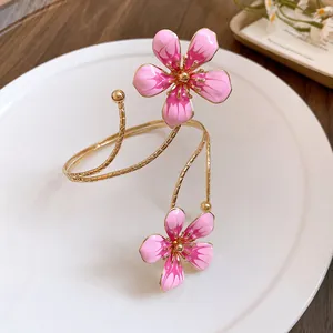 Close-up macro view of a vintage gold plated arm cuff with delicate pink enamel flowers
