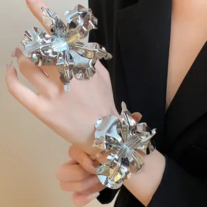 Detail shot of oversized silver metallic flower ring and bracelet set on model