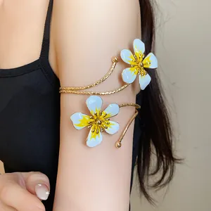 Close-up of elegant gold metal arm cuff with blue enamel flower details