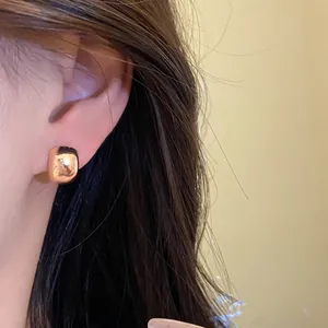 Primer plano de un elegante pendiente geométrico de oro rosa pulido colocado en la oreja
