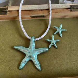 Gros plan du pendentif étoile de mer turquoise avec collier en corde blanche.