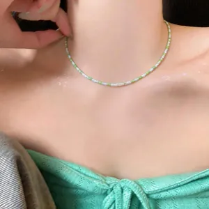 Close-up view of a fresh green and white glass bead necklace worn on a woman's neck