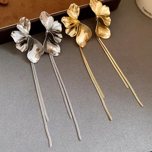 Close-up detail of elegant gold and silver floral earrings with delicate long fringe tassels