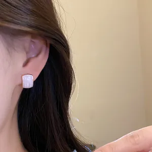 Primer plano detallado que muestra la textura nacarada de los pendientes cuadrados de resina
