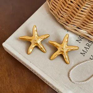 Vue détaillée en gros plan de pendentifs étoiles de mer dorées sur un livre vintage.