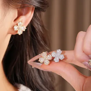 Close-up of zircon flower ear clips in gold and silver finishes on a model's ear