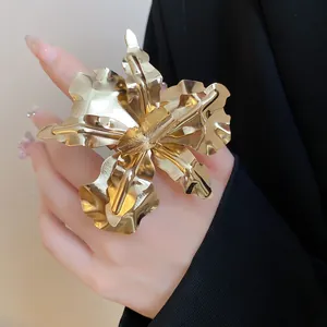 Macro view of oversized gold metal orchid flower ring on hand with elegant black sleeve