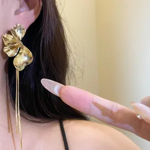 Detailed view of gold flower tassel earrings worn on ear showing elegant long chains.