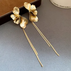 Detailed close-up of golden flower petal earrings featuring elegant long snake chain tassels