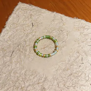 Detailed close-up view of a minimalist handmade ring featuring green and clear glass beads