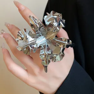 Detailed close-up showing the metallic texture of a large silver flower-shaped ring