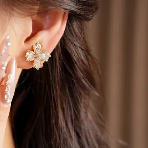Close-up view of gold plated flower ear clip featuring sparkling zirconia stones on model