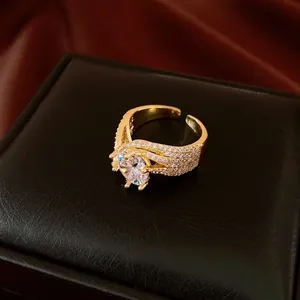 Detailed view of gold-tone open ring with twisted band and sparkling zircon stones