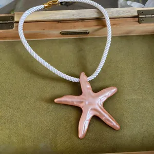 Vue détaillée d'un grand pendentif étoile de mer pêche sur un collier en cordelette blanche