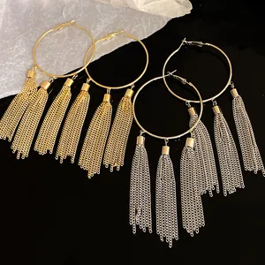 Close-up of elegant gold and silver hoop earrings featuring long vintage chain tassels