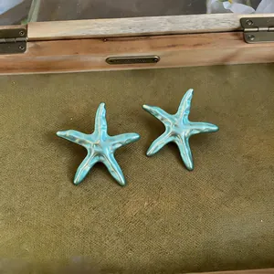 Gros plan de pendentifs étoile de mer en émail bleu clair perlé avec texture détaillée