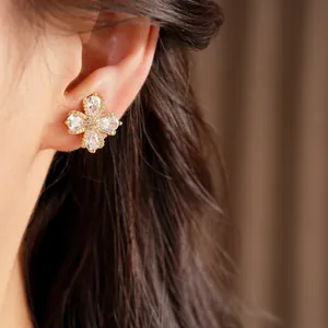 Detail shot of a sparkling gold-plated flower ear clip inlaid with clear zircons.