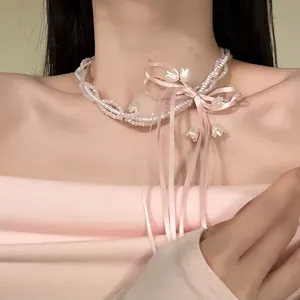Close-up detail of pink ribbon bow necklace with lily of the valley charms on female model