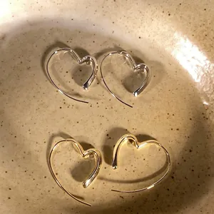 Exquisite detail of minimalist hollow heart-shaped hoop earrings in gold and silver tones