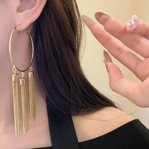 Elegant close-up view of gold hoop earrings featuring long chain tassels worn by model
