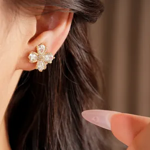 Detailed view of gold-plated flower stud earring with shimmering cubic zirconia on ear