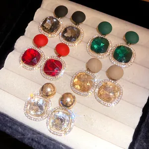 Variety of elegant crystal drop earrings with matte round tops in a jewelry box.