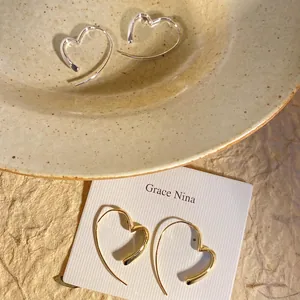 Close-up of elegant hollow heart ear hooks in gold and silver finishes